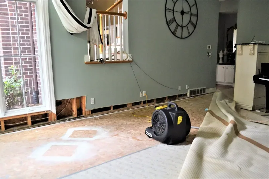 A restoration crew setting drying equipment inside a water-damaged home