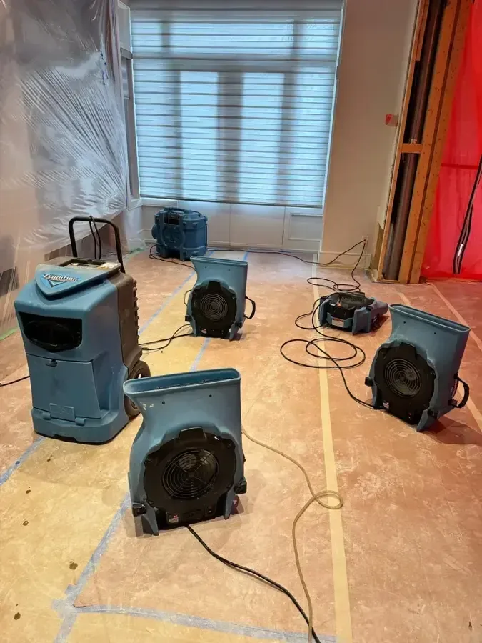 Dehumidifiers and air movers drying a room over protected flooring