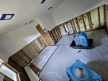 Flood-cut walls with air movers and plastic sheeting drying a room