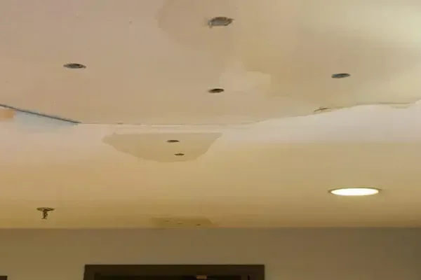 A ceiling stained in a wide patch around recessed lights after a leak from above