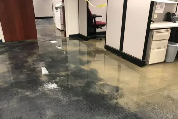 Standing water spread over an office floor between rows of cubicles