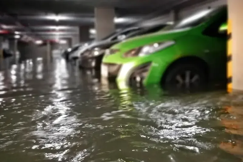 Storm runoff rising around parked cars in a flooded parking garage after heavy rain