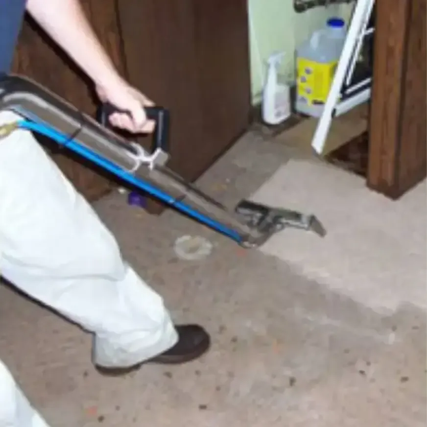 A technician running an extraction wand over a soaked floor to pull the water out