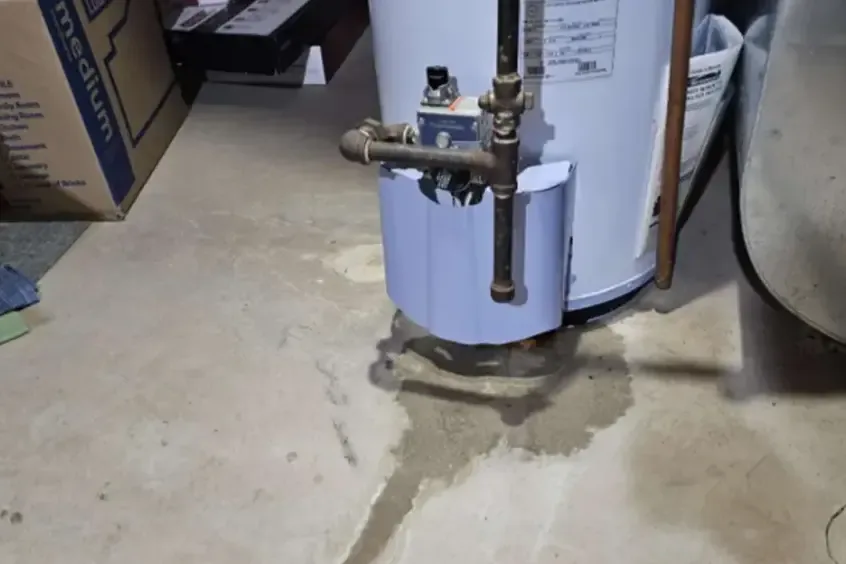 Water spreading over a concrete garage floor from a failing water heater tank